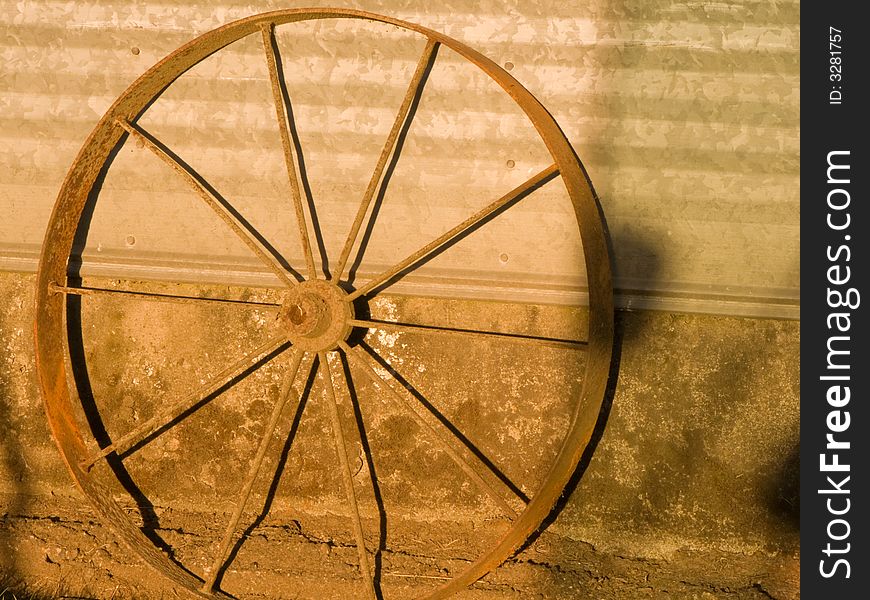 Antique wheel leaning against tin shed