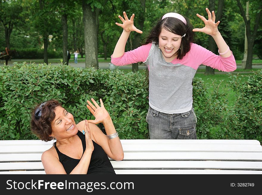 Mother sits on the bench, daughter stands near. Mother sits on the bench, daughter stands near