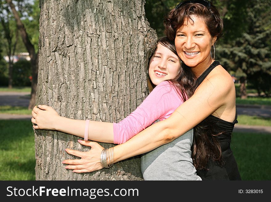 Mother and daughter embrace the tree