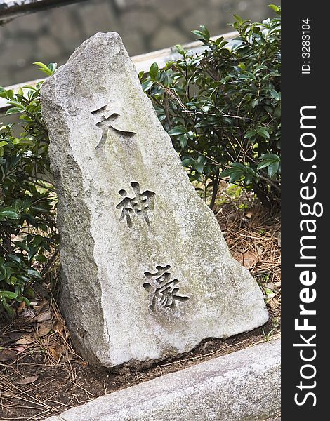 Stone with Japanese Writing sits in a Japanes garden.