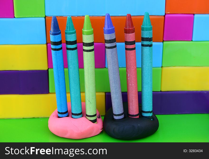 Six crayons standing upright held in place by clay