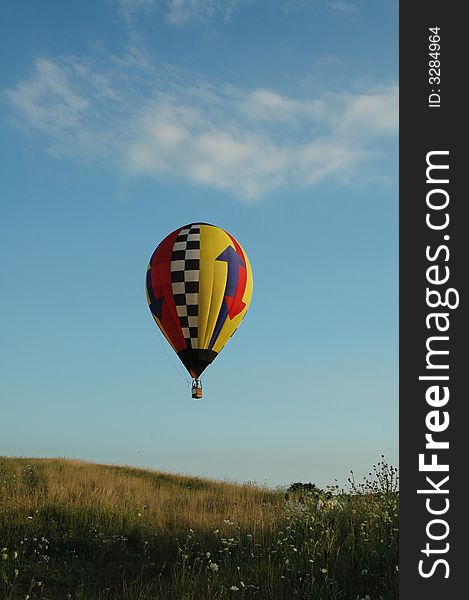 Hot air balloon floating over field. Hot air balloon floating over field