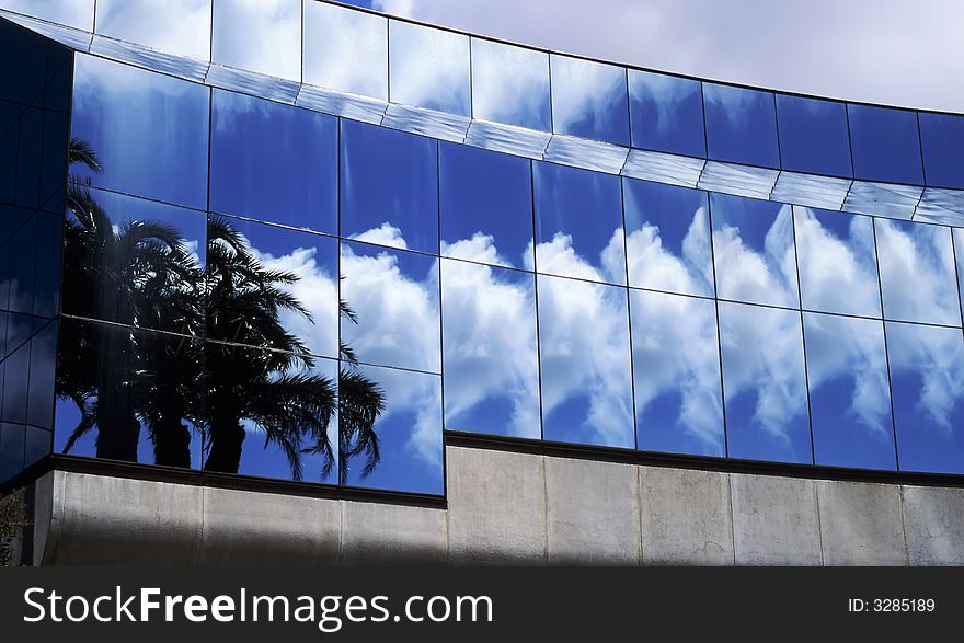 Palm trees, clouds, blue sky reflect and repeat in building window glass. Palm trees, clouds, blue sky reflect and repeat in building window glass