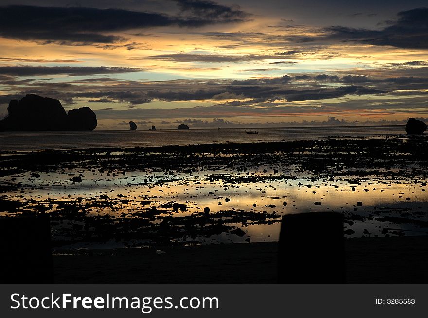 The sun sets in Hat Rai Lay as the tide goes out revealing a stony beach on the Andaman Coast. The sun sets in Hat Rai Lay as the tide goes out revealing a stony beach on the Andaman Coast.