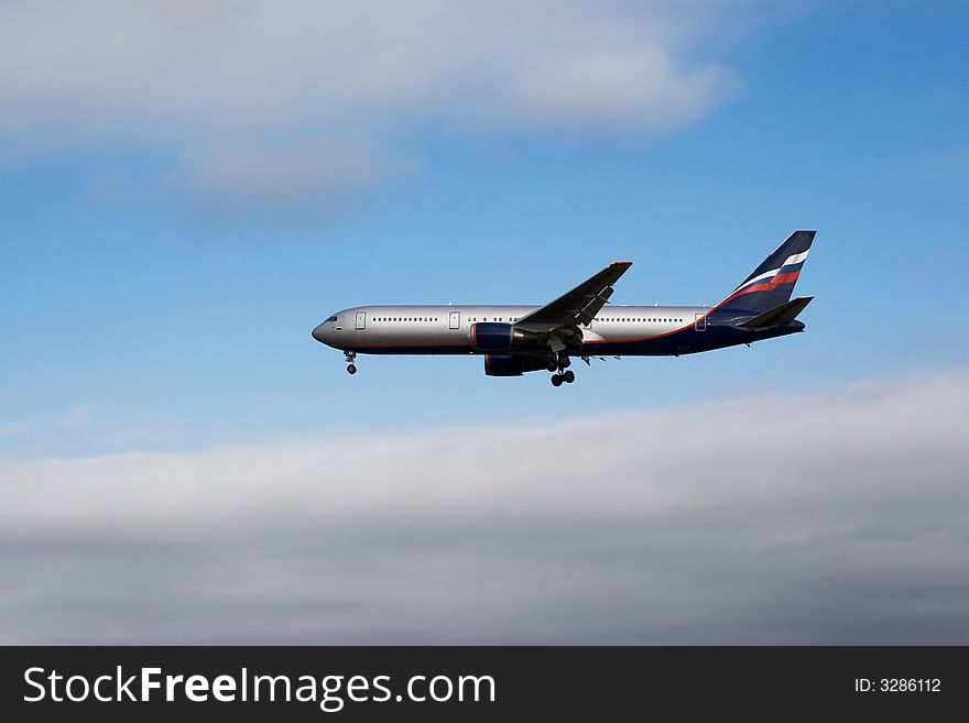 Airplane landing with blue sky and clouds in background