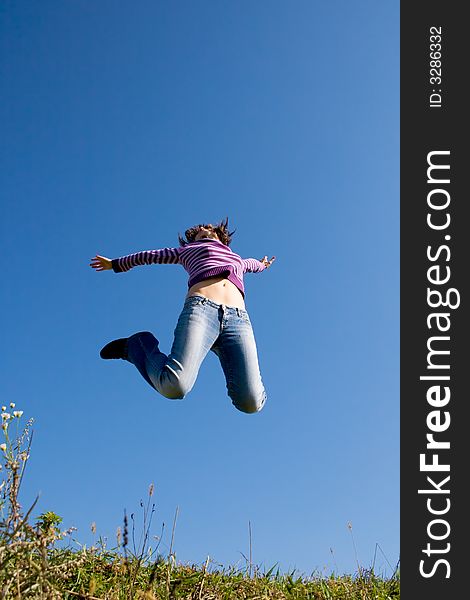 Girl jumping high, blue sky in background