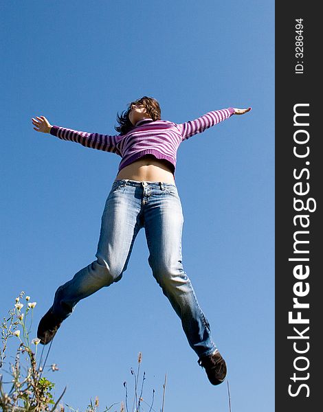 Girl jumping high, blue sky in background