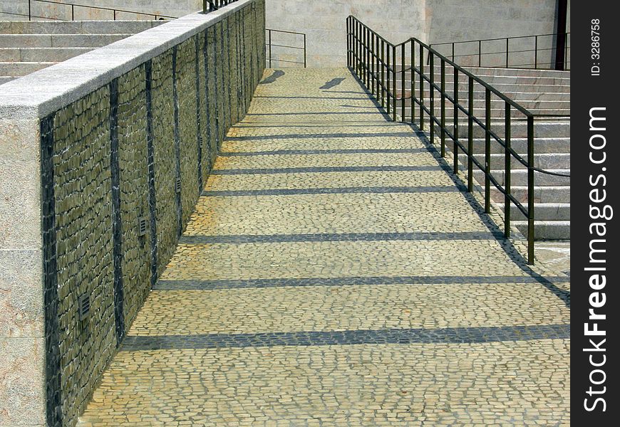 Portuguese sidewalk with white and black stones and a hand rail. Portuguese sidewalk with white and black stones and a hand rail