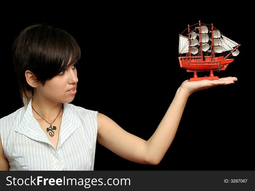 The nice girl with the toy ship in a hand, isolated on black background. The nice girl with the toy ship in a hand, isolated on black background