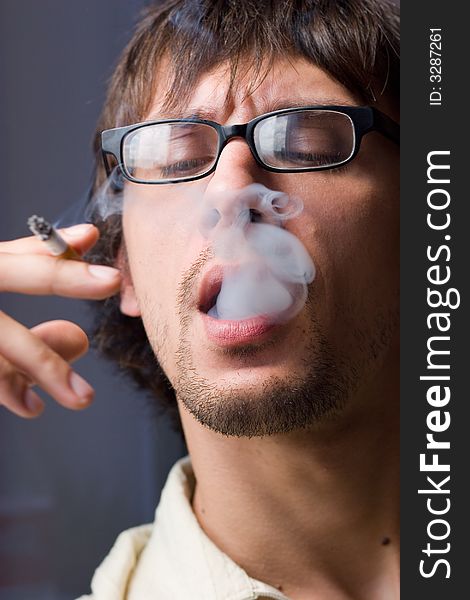 Young man with glasses a-smoke. Young man with glasses a-smoke