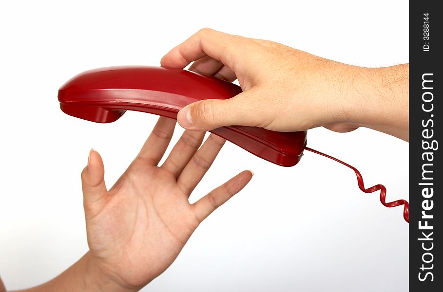 A hand passing a red phone while another hand reaches for it. A hand passing a red phone while another hand reaches for it
