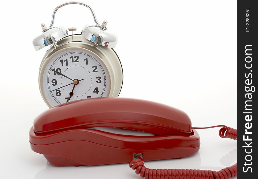 Photo of a telephone and an alarm clock over a white background. Photo of a telephone and an alarm clock over a white background