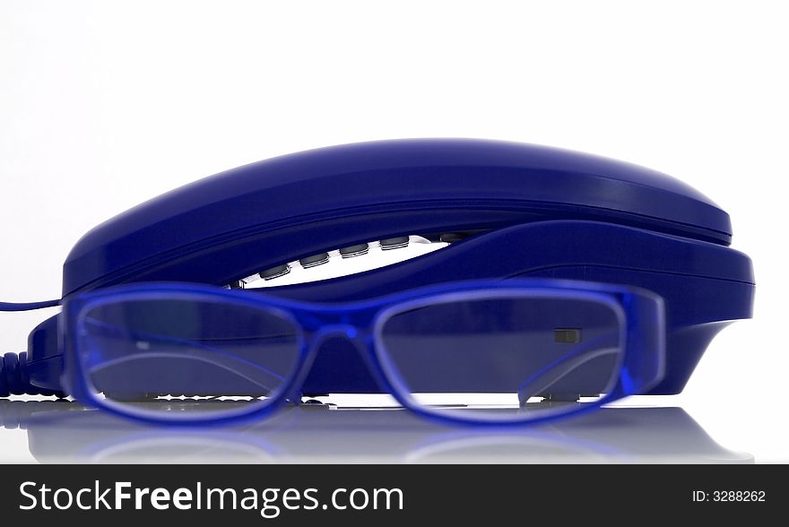 Photo of a telephone and eyeglasses over a white background
