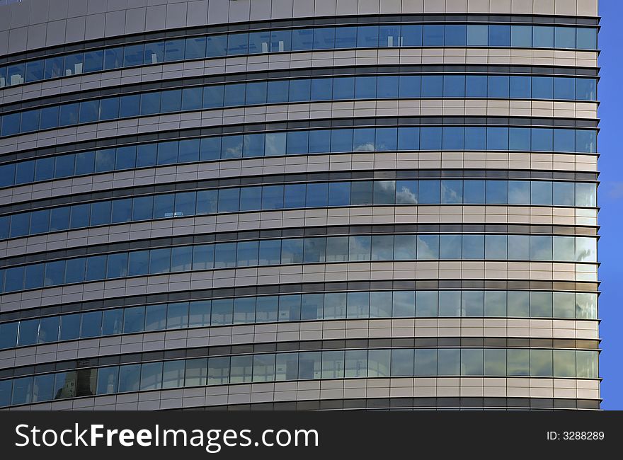 Modern  round tower skyline. Glass and metal on blue clear sky.Clouds reflexions. Modern  round tower skyline. Glass and metal on blue clear sky.Clouds reflexions.