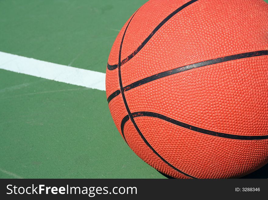 A Basketball on green court with white line. A Basketball on green court with white line