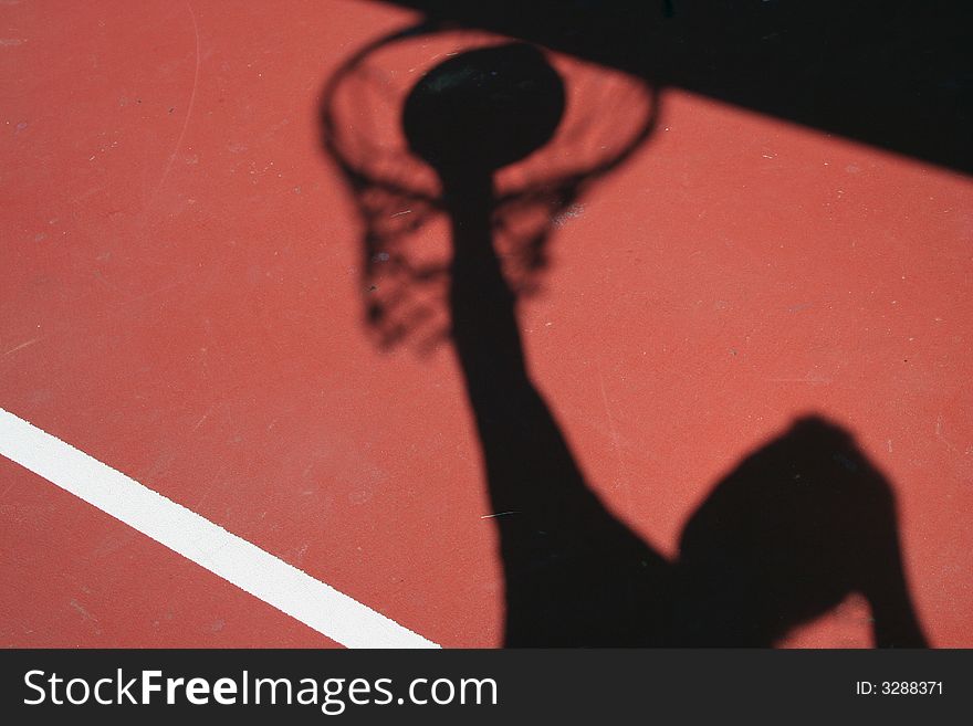 A Shadow Basketball player dunking on red court
