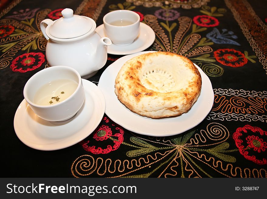 Teapot with cups and griddle on carpet