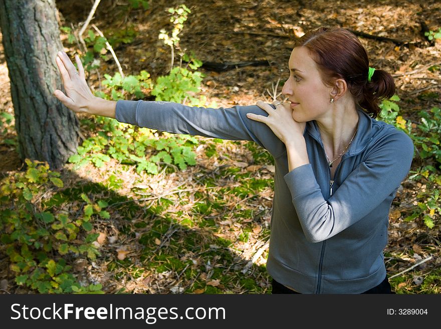 A woman practices stretching in autumn forest