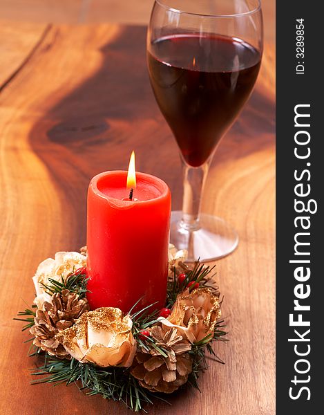 Christmas candle and a glass of wine on a wooden table. Christmas candle and a glass of wine on a wooden table