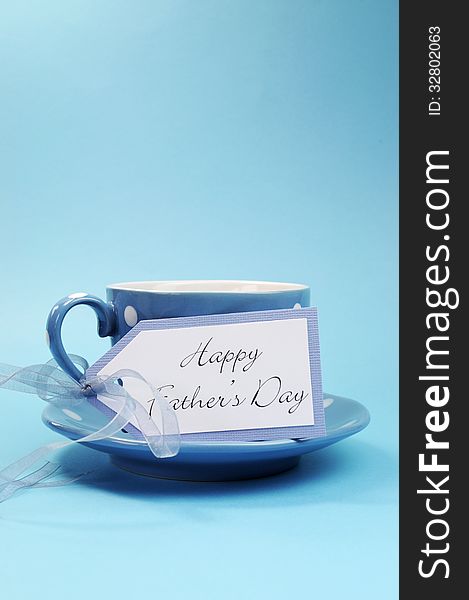 Happy Fathers Day gift tag with a cup of coffee or tea for Dad in a blue polka dot cup and saucer against a blue background. Vertical with copy space for your text here. Happy Fathers Day gift tag with a cup of coffee or tea for Dad in a blue polka dot cup and saucer against a blue background. Vertical with copy space for your text here.