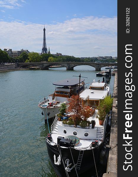 Party Boats Moored On The Seine River With Eiffel Tower In Backg