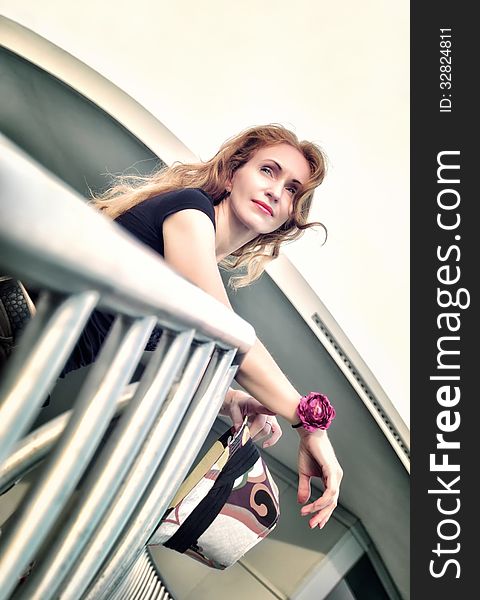 Portrait of thinking beautiful woman standing on the stairs.