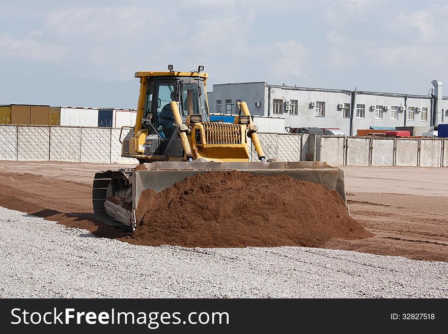 Crawler tractor pushes the sand at a construction site