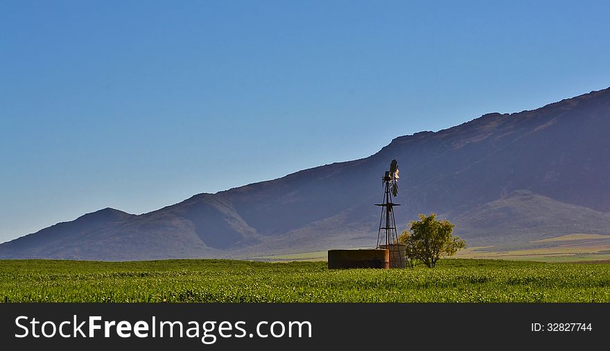 Landscape with hill and water pump windmill