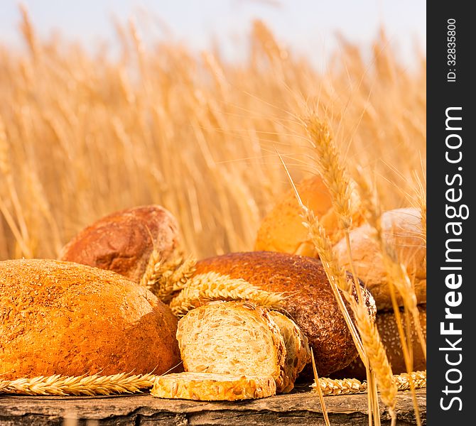 Homemade bread and wheat on the wooden table in autumn field