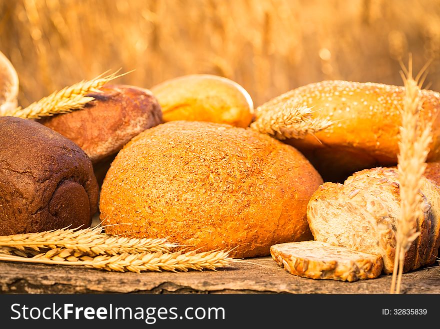 Homemade bread and wheat on the wooden table in autumn field