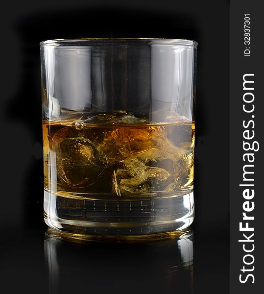 Whiskey with ice in a glass on a black background