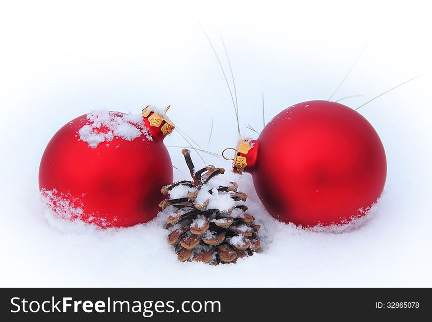 Two red Christmas balls and pine cone and dried up last years grass in the snow. Two red Christmas balls and pine cone and dried up last years grass in the snow