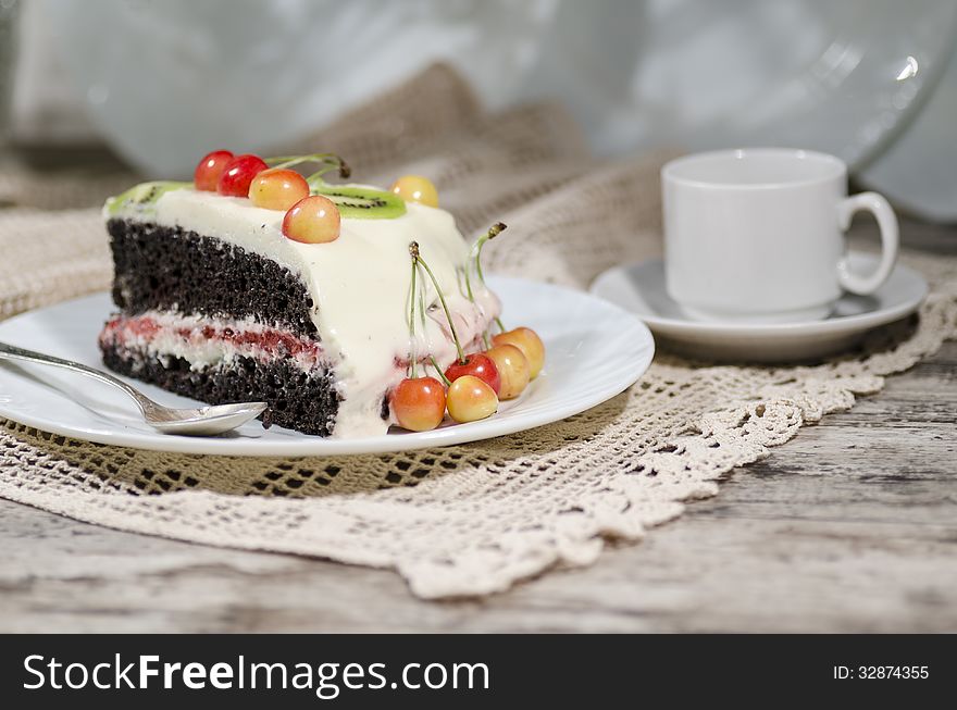 Slice of bird-cherry flour cake with cherries, strawberries and cup of coffee