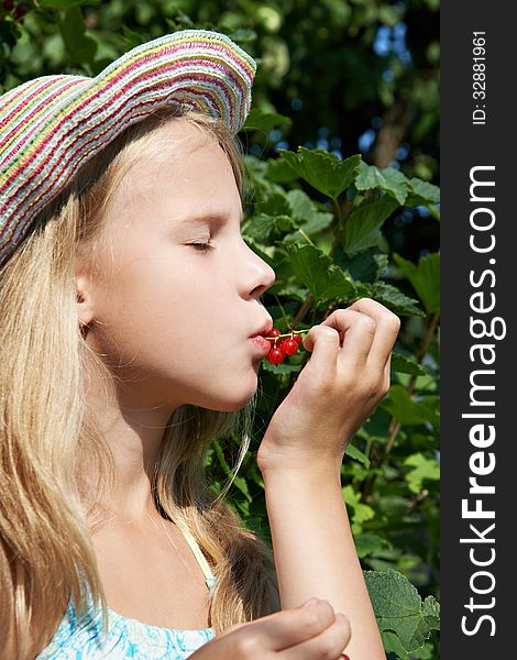 Girl eats red currant in the garden