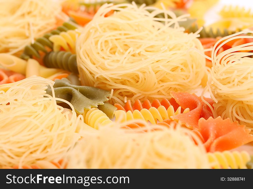 Different pasta in three colors close-up on the white background. Different pasta in three colors close-up on the white background.