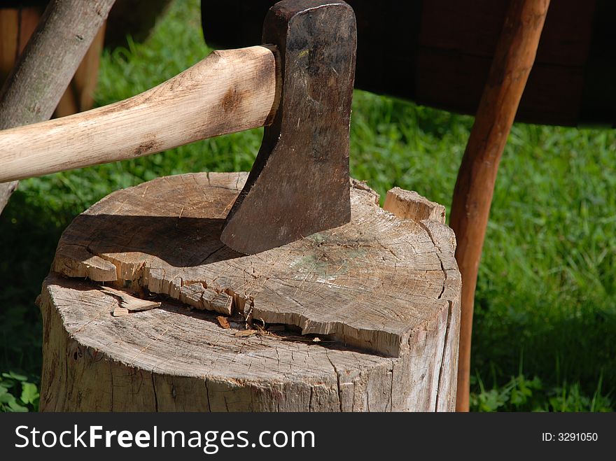 An ax imbedded in a log of wood. An ax imbedded in a log of wood