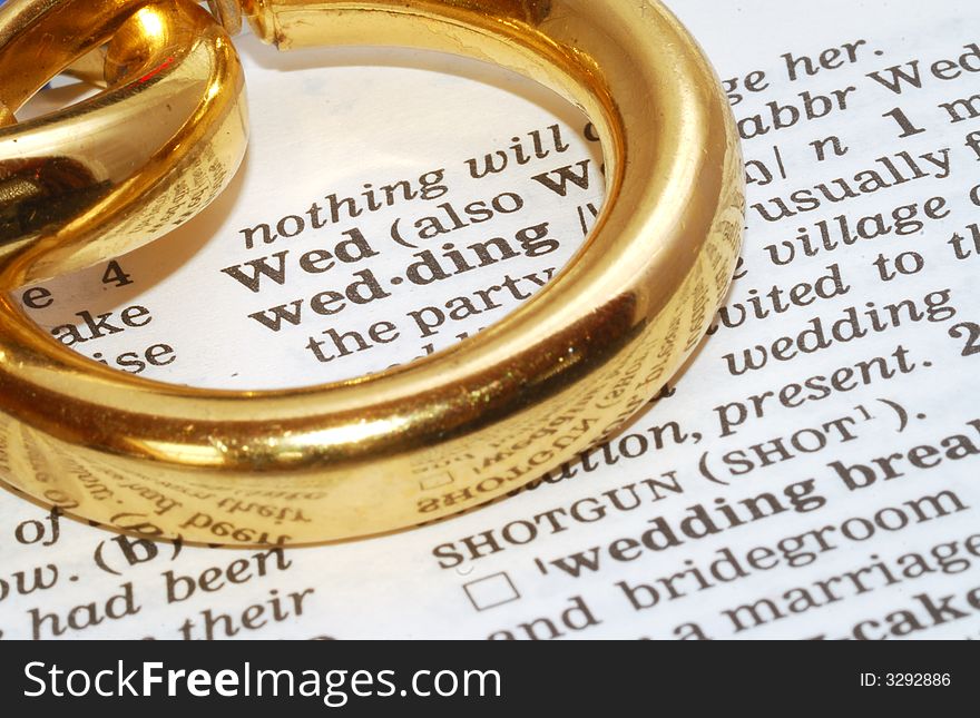 The word wedding out of a dictionary with gold rings next to it. The word wedding out of a dictionary with gold rings next to it