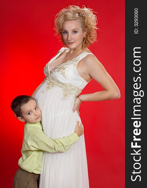 Gorgeous pregnant blond woman with her first child together. on red background. Gorgeous pregnant blond woman with her first child together. on red background.