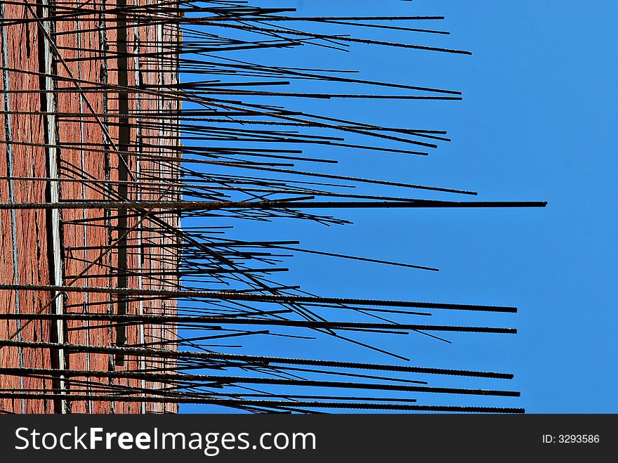 Unfinished side of building with protruding steel elements itno the blue sky. Unfinished side of building with protruding steel elements itno the blue sky