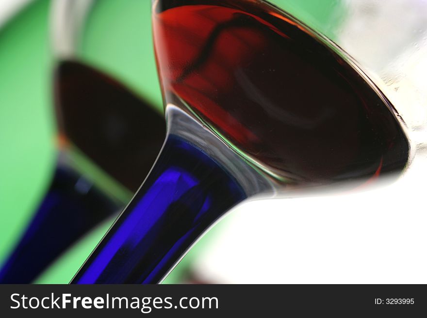 Two glasses of  red wine with blue stems and a green bottle. Two glasses of  red wine with blue stems and a green bottle.