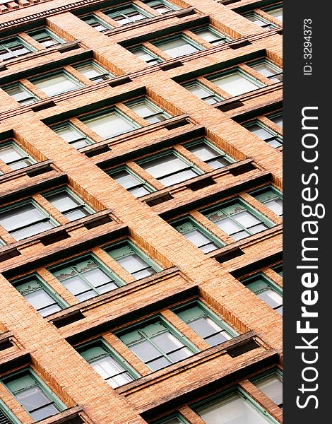 The side of a building composed of windows and red brick. The side of a building composed of windows and red brick.