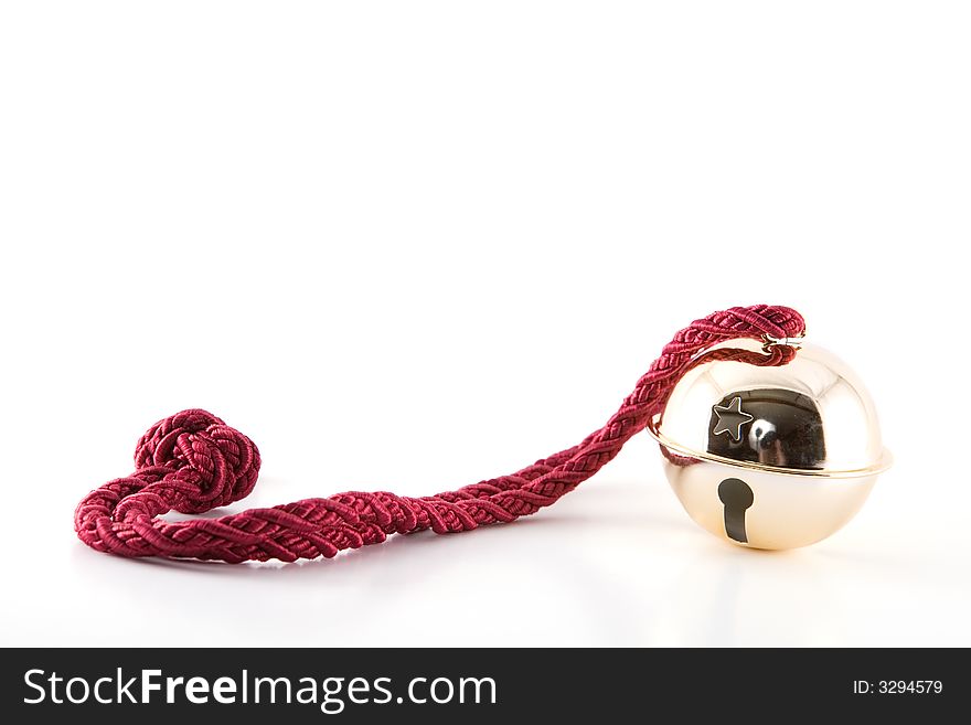 A shiny gold jingle bell on a fancy red rope. A shiny gold jingle bell on a fancy red rope.