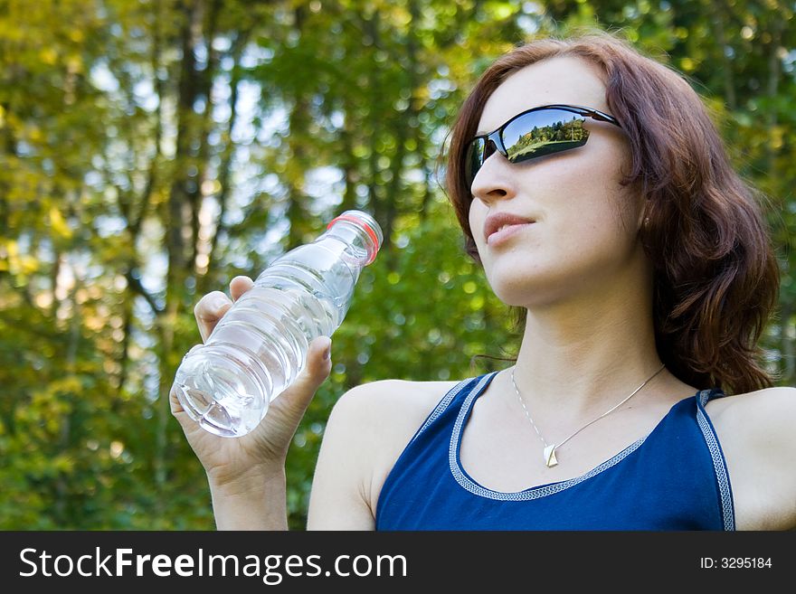 A young woman is drinking from bottle. A young woman is drinking from bottle