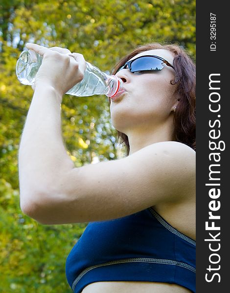 A young woman is drinking from bottle. A young woman is drinking from bottle