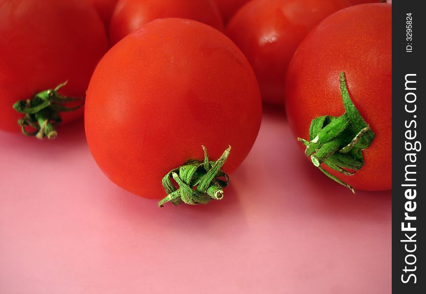 Many tomatoes over pink background