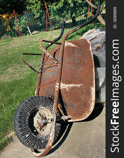 An old well used wheel barrow standing up in the garden. An old well used wheel barrow standing up in the garden.