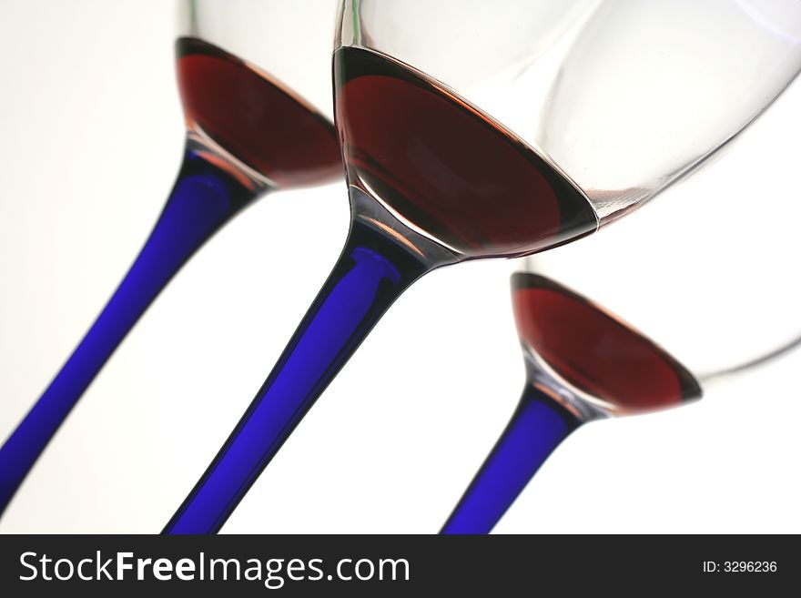 Three glasses of red wine with blue stems on an angle. Three glasses of red wine with blue stems on an angle.