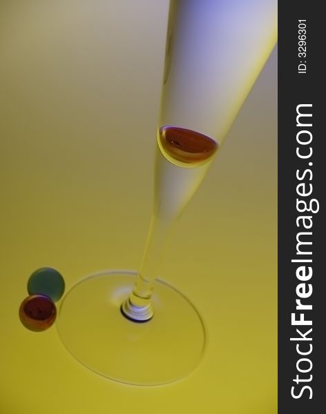 Thin glass with two peaces of red balls on the colorful background. Thin glass with two peaces of red balls on the colorful background