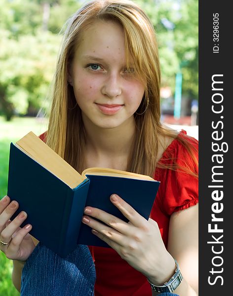 School girl readin the book and looking at camera.