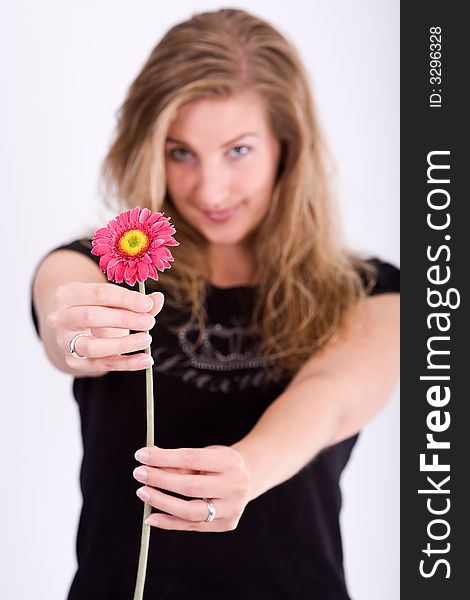 Nice, smiling woman holds Gerbera-flower while looking directly to you. Focus on flower. Nice, smiling woman holds Gerbera-flower while looking directly to you. Focus on flower.